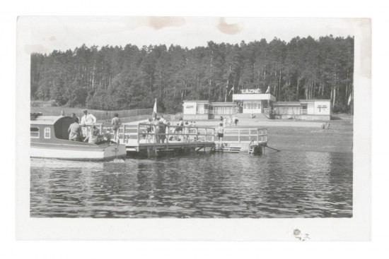 Bezprostředně po dokončení přehradní hráze na jaře 1934 začíná na Vranovské přehradě fungovat veřejná lodní doprava. První motorová loď J. Máša začala brázdit zdejší vody 11. července 1934. Na pláži proběhla výstavba budovy lázní s přístavním můstkem pro lodě. Za nimi je vidět jeden ze dvou stožárů, který zde vybudovala ve 40. letech německá armáda na obranu hráze. Byla mezi nimi zavěšena ocelová síť pro zachytávání leteckých bomb svržených na přehradu. V 60. letech pak byly z bezpečnostních důvodů odstraněny.