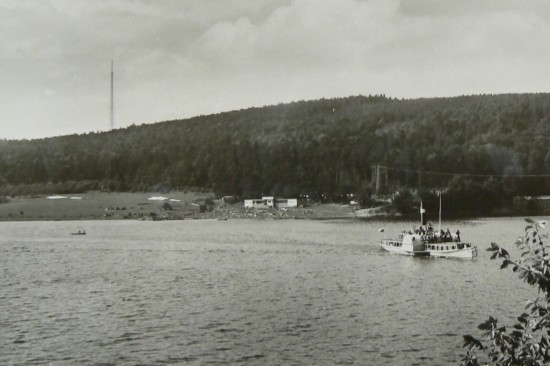 V pozadí lodí jsou vidět vysoké ocelové stožáry, které v letech 1943–1944 vybudovala německá armáda na obranu hráze Vranovské přehrady. Byla mezi nimi zavěšena ocelová síť, která měla zachytávat bomby vržené na přehradu při předpokládaných leteckých útocích. Dva ocelové stožáry vysoké 110 m umístěné na obou březích naproti sobě ve vzdálenosti 500 m zde stály ještě v 60. letech 20. století. Pak byly z bezpečnostních důvodů odstraněny.